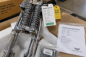 A detailed view of a chrome springer front end assembly with visible inspection tags and packing documentation