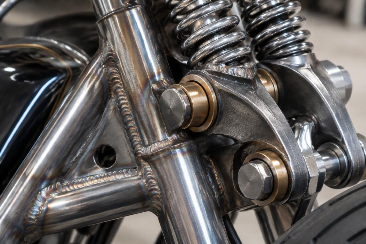 Close-up detail of TIG-welded construction and bronze rocker bushings on the springer assembly