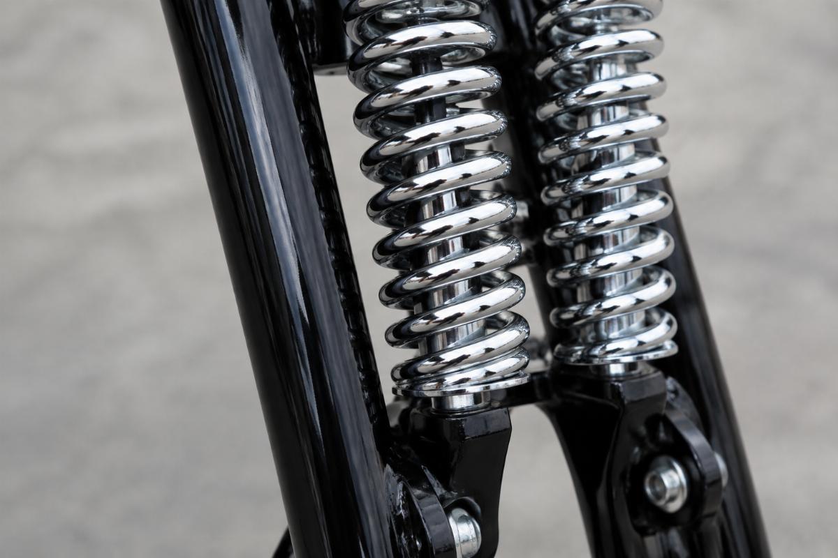 Close up of black legs and chrome springs on inline spring fork assembly