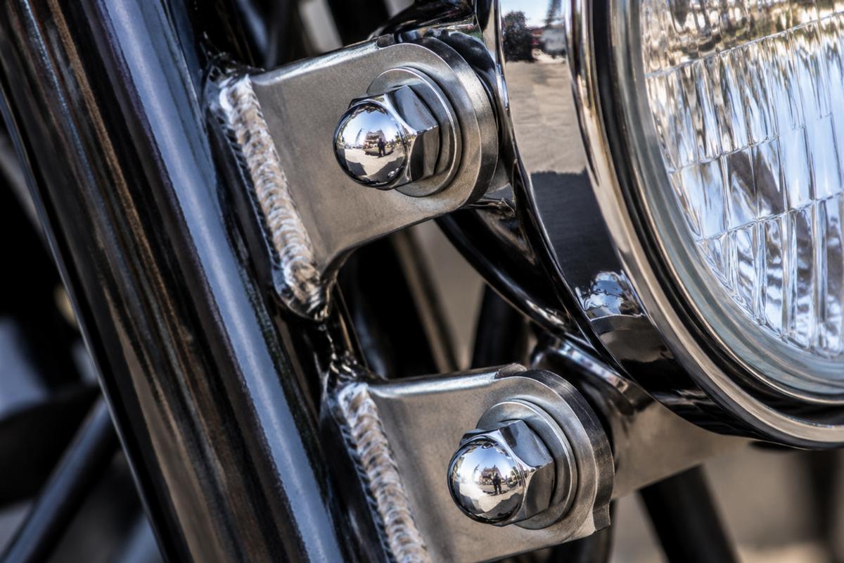 Close up of chrome acorn nuts and welded headlamp brackets