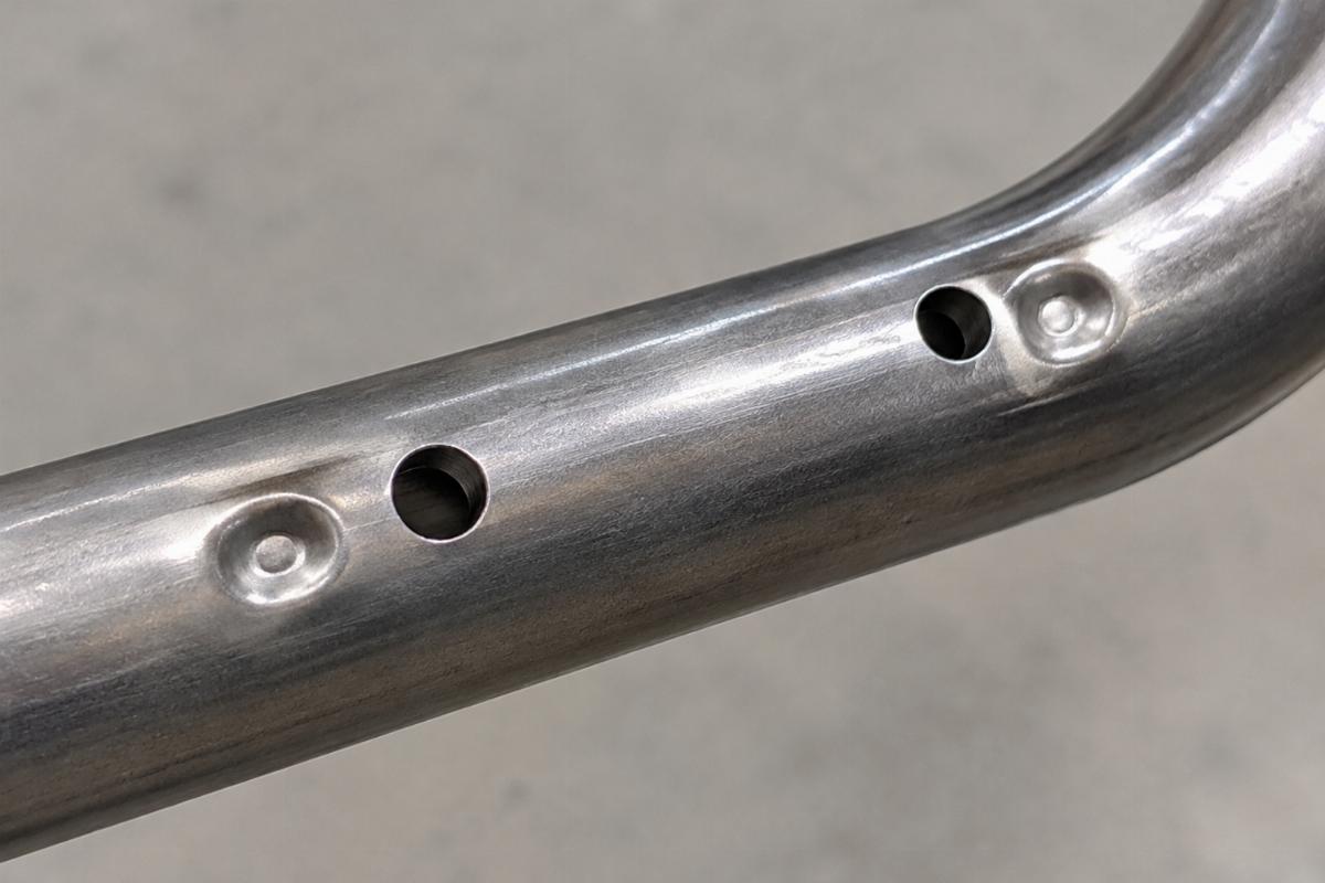 Close up of drilled wire harness clip holes and dimples on 1 inch steel handlebars