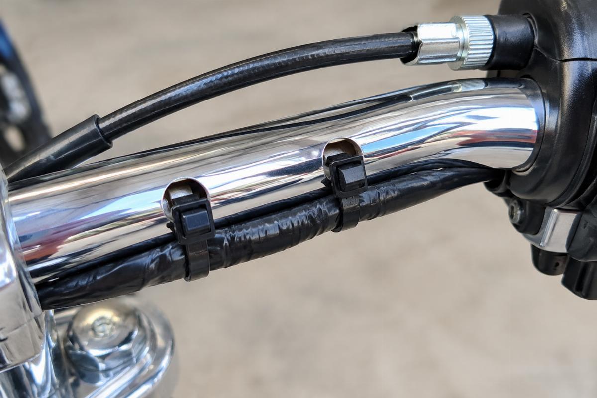 Close up of drilled wire harness clip holes and external throttle cable clearance on chrome handlebars