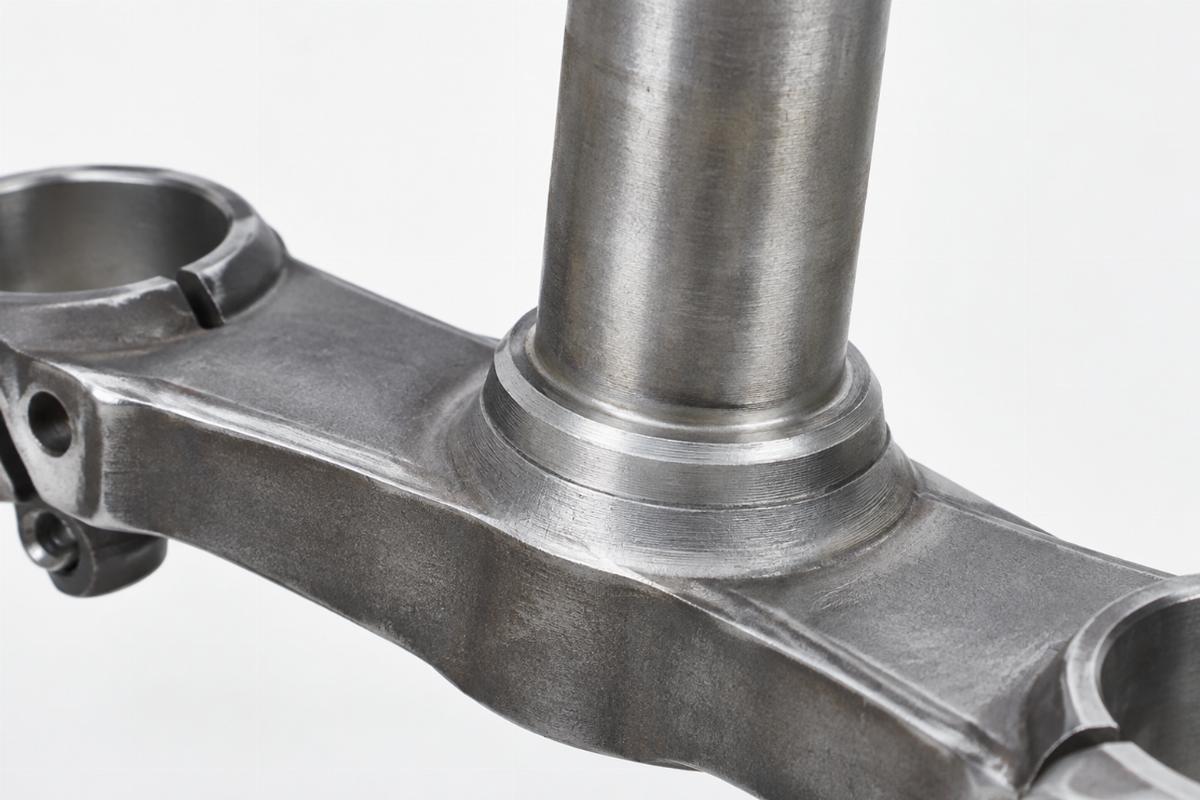 Close up of raw steel spring fork stem motorcycle aftermarket part showing unwelded preparation surface