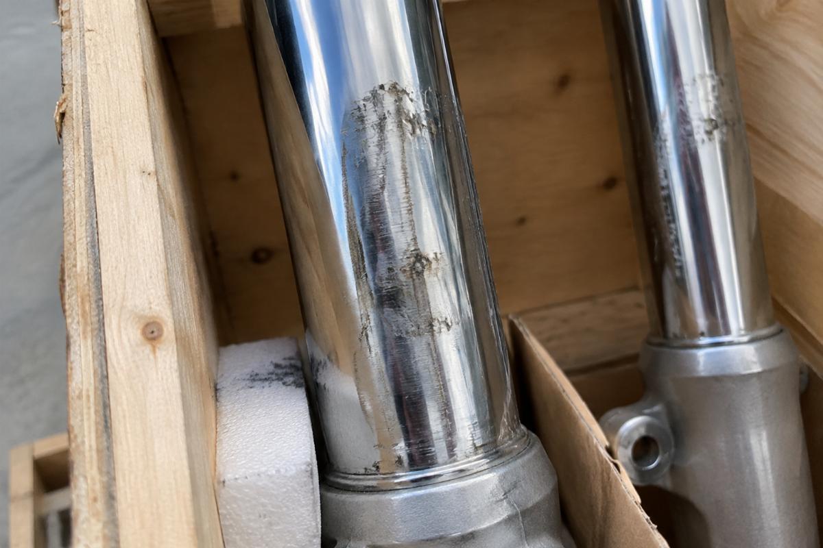 Close-up of vibration damage on chrome fork legs due to insufficient blocking inside a crate